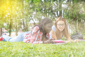 Teenagers friends laying on the grass, sun rays coming from the sky