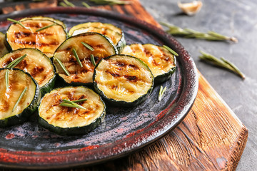 Plate with tasty grilled zucchini on wooden board, closeup