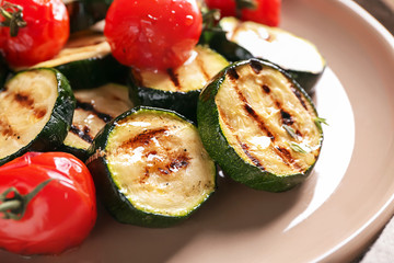 Tasty grilled zucchini with tomatoes on plate, closeup