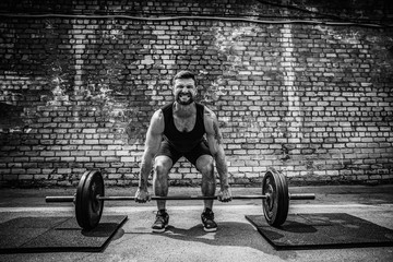 Muscular fitness man doing deadlift a barbell in outdoor, street gym. Functional training. Snatch...