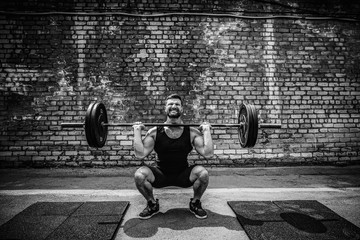 Muscular fitness man doing deadlift a barbell over his head in outdoor, street gym. Functional...