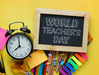 World Teacher's Day Text. Alarm Clock, Blackboard and School Stationary on Yellow Background