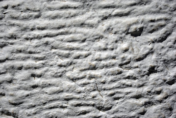 Wall with gray plaster imitating waves on water surface, grunge texture background