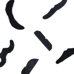 Black mustache lying on a white table. Minimalistic style. Top view. Flat lay. Concept of Prostate Cancer Awareness Month.