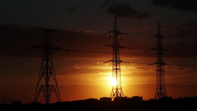 Electricity pylon with stormy sky on the background. Timelapse of sunset. Zoom out 4K