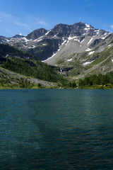 Naklejka na ściany i meble Alpine lake into the wild nature, between pines, rock and mountains