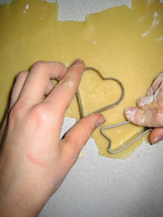 Hand making a heart-shaped christmas cookie out of dough