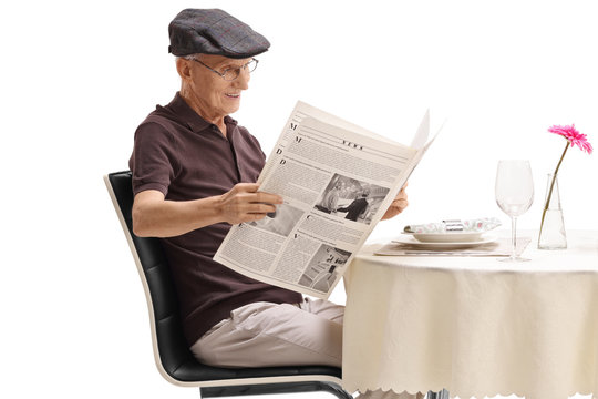 Senior seated at a restaurant table reading a newspaper