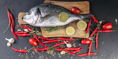 Food banner. Fresh Dorado on a wooden cutting board. Aromatic herbs, lime, cherry tomatoes, salt, paprika and spices.