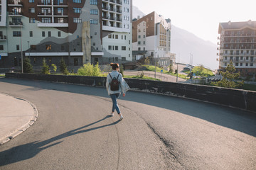 Rosa Khutor, Sochi, young woman is walking along the street of a ski resort at sunset