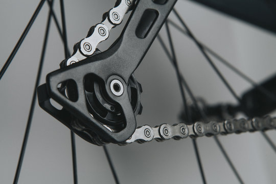 Detail of bicycle rear derailleur shifting arm with silver chain.