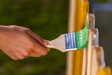 Painting a wooden fence with a wooden brush. Repairs concept