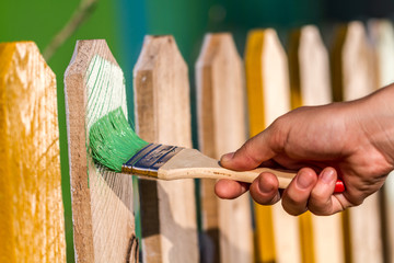Painting a wooden fence with a wooden brush. Repairs concept