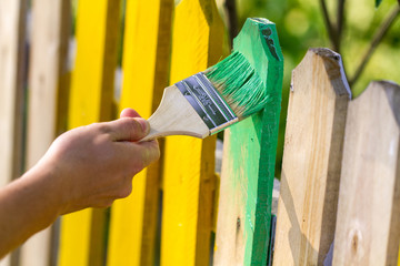 Painting a wooden fence with green paint. Repair concept