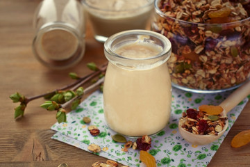 Obraz na płótnie Canvas Yogurt in a glass jar and granola in the background