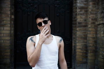 Young tattooed man smoking cigarette