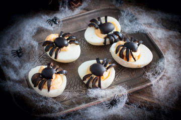 The idea for decorating a table for Halloween: stuffed eggs with spiders from olives, horizontal