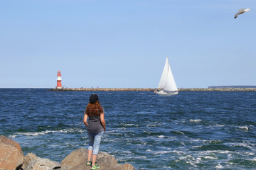 Warnemünde, Frau beobachtet ein Segelboot in Warnemünde 