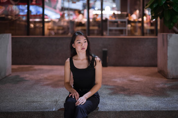 Portrait Of Beautiful Asian Woman Sitting Outdoors At Night