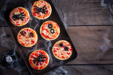 The idea of a festive meal for Halloween: mini pizza with spiders, mummy and spiderweb, copy space,...