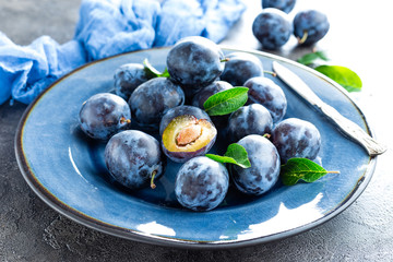 Fresh juicy sweet plums on plate with leaves