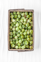 Gooseberries in a cardboard box on a white textured background..