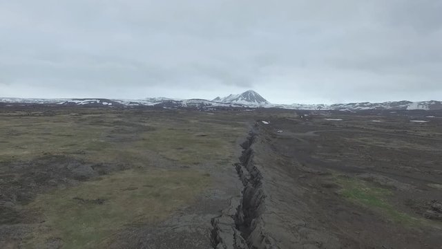 Drone flies above boundary between american and european tectonic plates. In background can be seen vulcano under the snow.