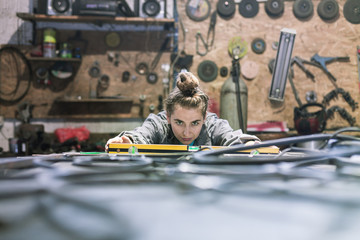 young woman in a workshop measuring