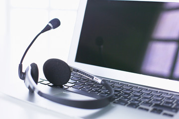 Communication support, call center and customer service help desk. VOIP headset on laptop computer keyboard