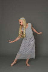 full length portrait of blonde girl wearing crow and grey dress, standing pose.  grey studio...