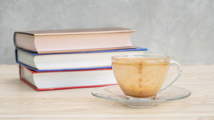 An empty of a cup of coffee and a pile of a book.