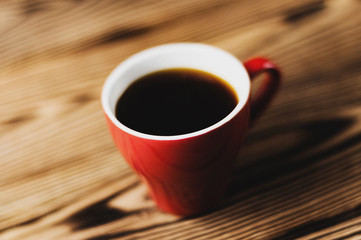 Full cup of black coffee on old wooden table. Morning concept
