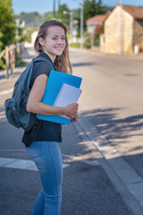 Back to school. Student girl holding books and carry school bag while walking to school. Urban background.