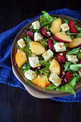 Fruit salad with arugula, plums, nectarines and soft cheese on a plate