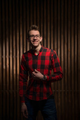 The guy in the plaid shirt. Guy in the interior. Young handsome guy. Man standing near the wooden walls.