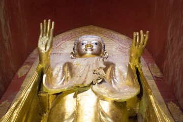A standing Bhddha statue in gold color