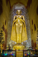 A standing Buddha statue in gold color