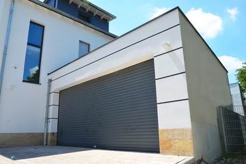 Moderne Beton-Garage mit Automatik-Tor in der Hauszufahrt - obrazy, fototapety, plakaty