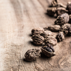 Black cardamom scattered on wooden background with copy space.