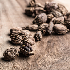 Black cardamom scattered on wooden background with copy space