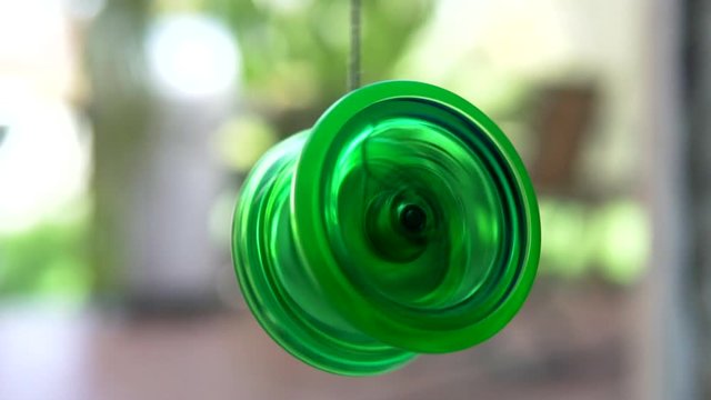 A green yo-yo spinning and loosing it's spin.