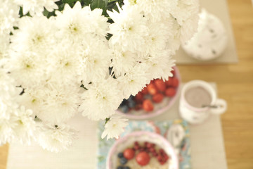 A large bouquet of white flowers on the table and breakfast for the family. Cozy house and delicious food. Seasonal Fruits, pastries and fragrant coffee. Copy space,,