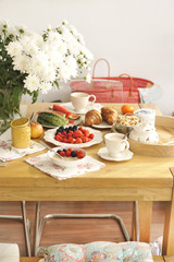 A large bouquet of white flowers on the table and breakfast for the family. Cozy house and delicious food. Seasonal Fruits, pastries and fragrant coffee. Copy space,