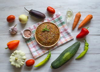 Cold vegetable snack in a plate and vegetables on a white wooden table.