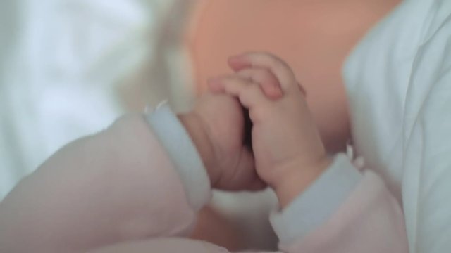 A closeup of a little baby's clasped hands. They are moving slowly while the baby is lying on her back and looking at them