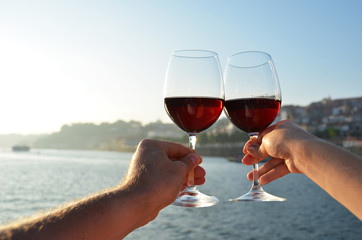 Wine glasses in the hands against Douro river in Porto, Portugal