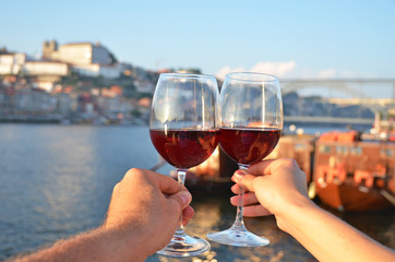 Wine glasses in the hands against Douro river in Porto, Portugal