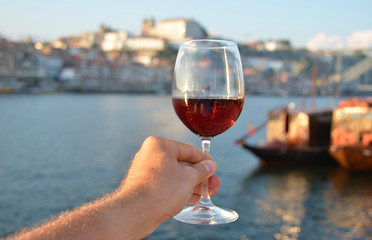 Wine glasses in the hands against Douro river in Porto, Portugal