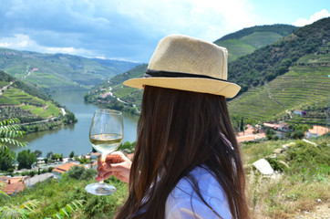 Girl with a glass of wine looking to the vineyards in Douro Valley, Portugal