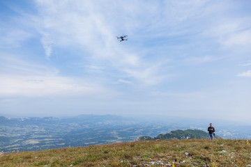 Naklejka na ściany i meble Young man flying drone over mountain